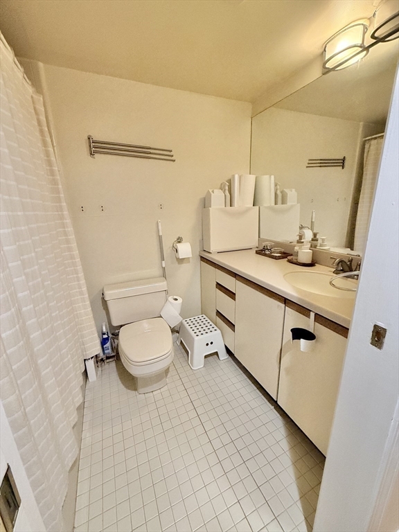 20 Webster Street, Unit 307 Brookline, MA 02446 - Photo 23 of 31 a bathroom with a granite countertop sink a toilet and a mirror