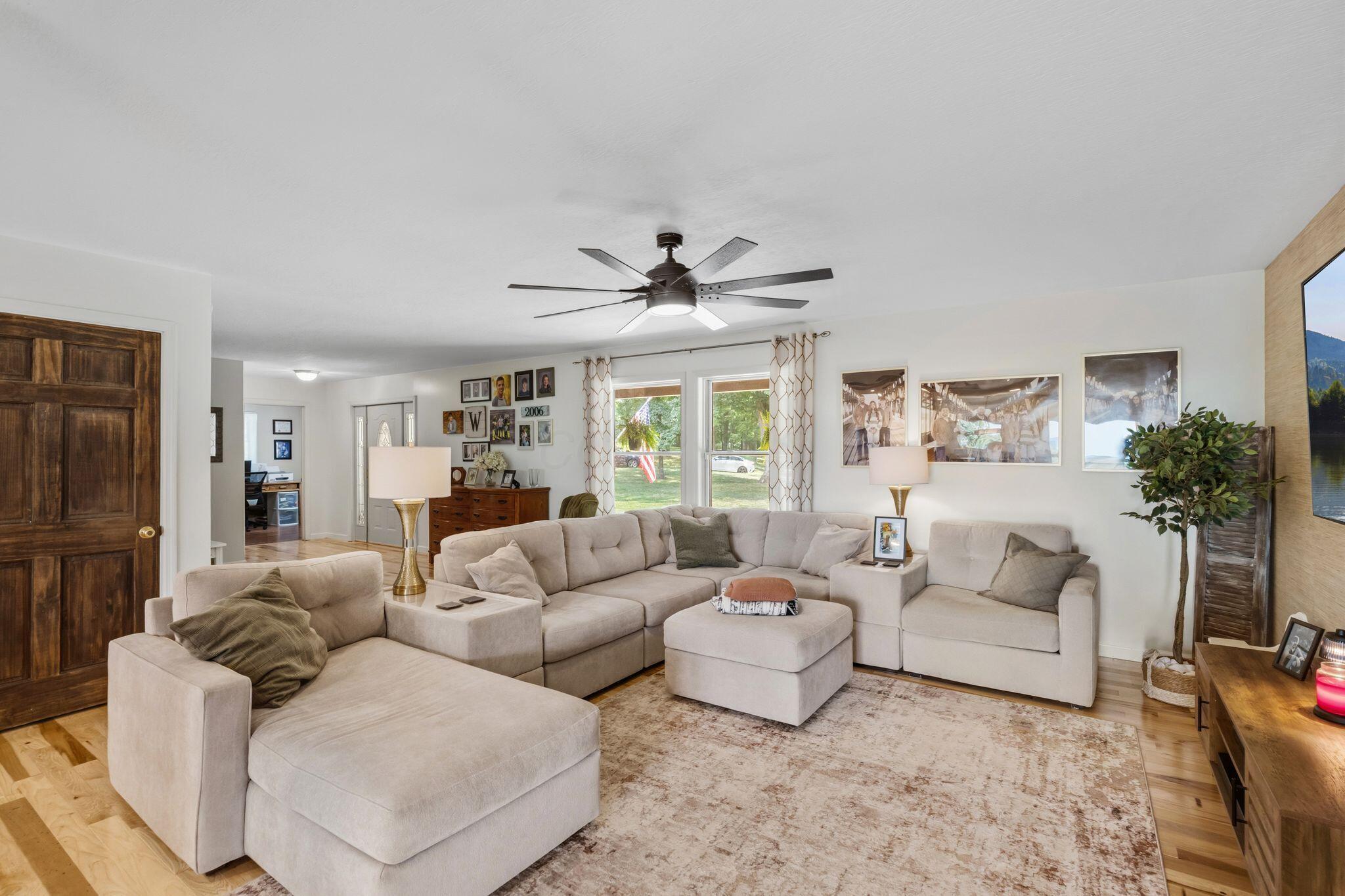 10446 Rich Hollow Road Southwest Lancaster, OH 43130 - Photo 32 of 83 Spacious living area featuring light wood-finish flooring, a contemporary ceiling fan, and large windows with patterned drapes