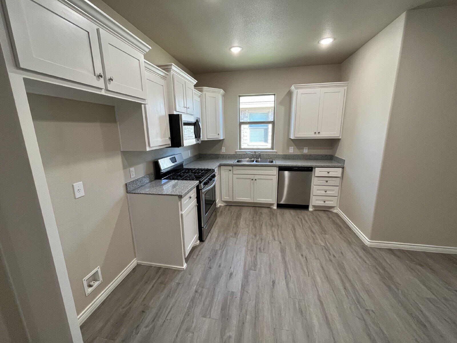 7010 12th Street Lubbock, TX 79416 - Photo 3 of 13 a kitchen with granite countertop a sink cabinets and wooden floor