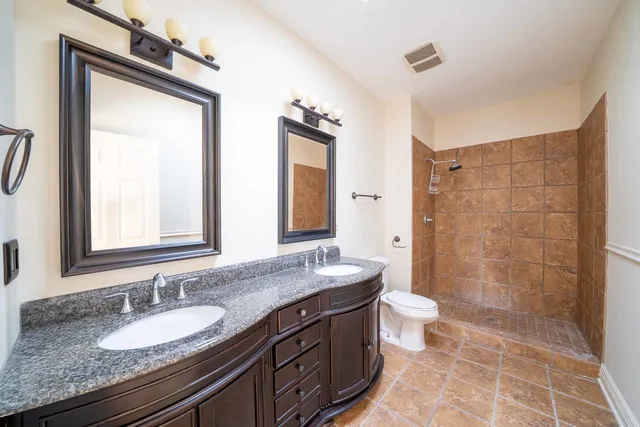 a bathroom with a granite countertop sink toilet a mirror a vanity and shower