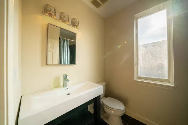 a bathroom with a toilet a sink a mirror and a window