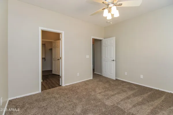 an empty room with closet and a chandelier fan