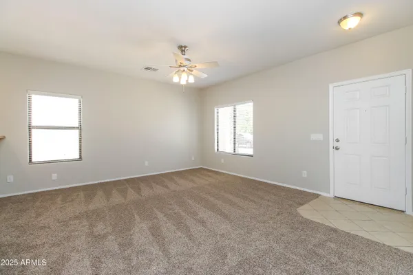 an empty room with windows and ceiling fan