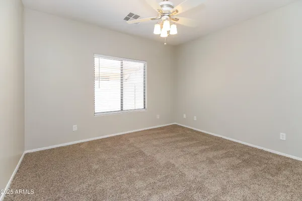 an empty room with a window and a chandelier fan