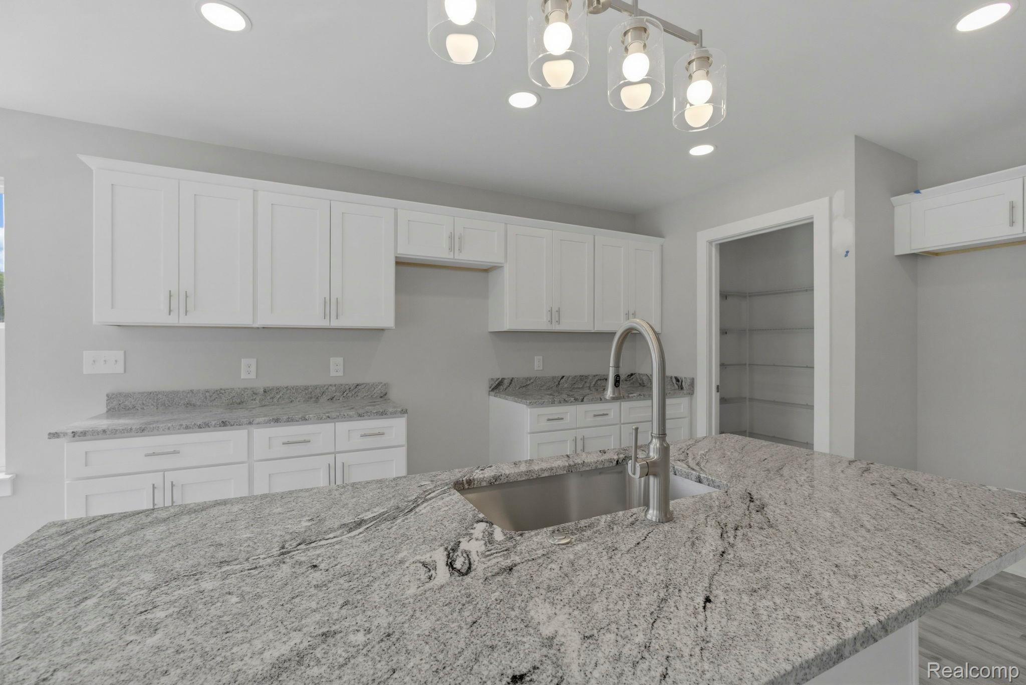 2281 Baltimore Davison, MI 48423 - Photo 8 of 26 Kitchen with light stone counters, white cabinets, decorative light fixtures, and a center island with sink