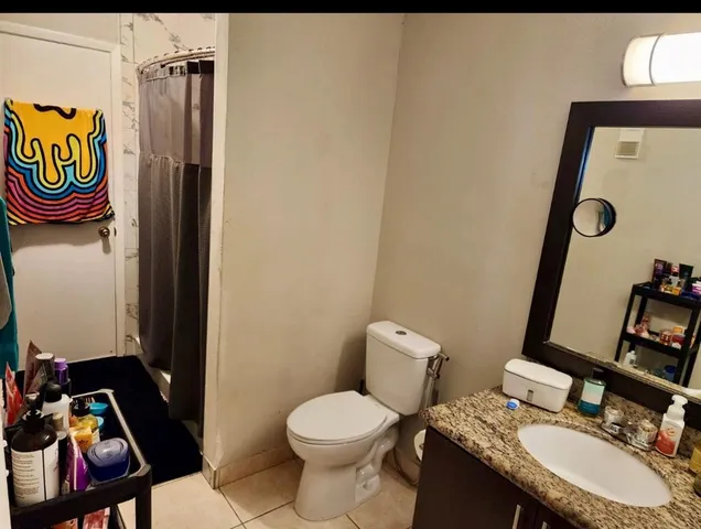 a bathroom with a granite countertop toilet sink and mirror