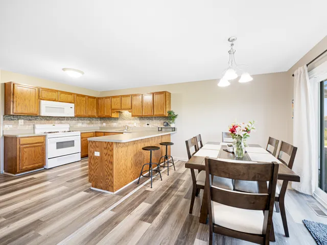 a kitchen with kitchen island a stove a table and chairs in it