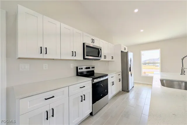 a kitchen with cabinets stainless steel appliances a sink and wooden floor