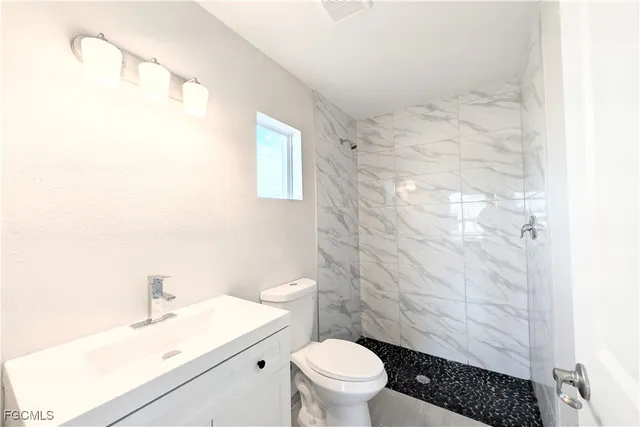 a bathroom with a sink a toilet a shower and a mirror