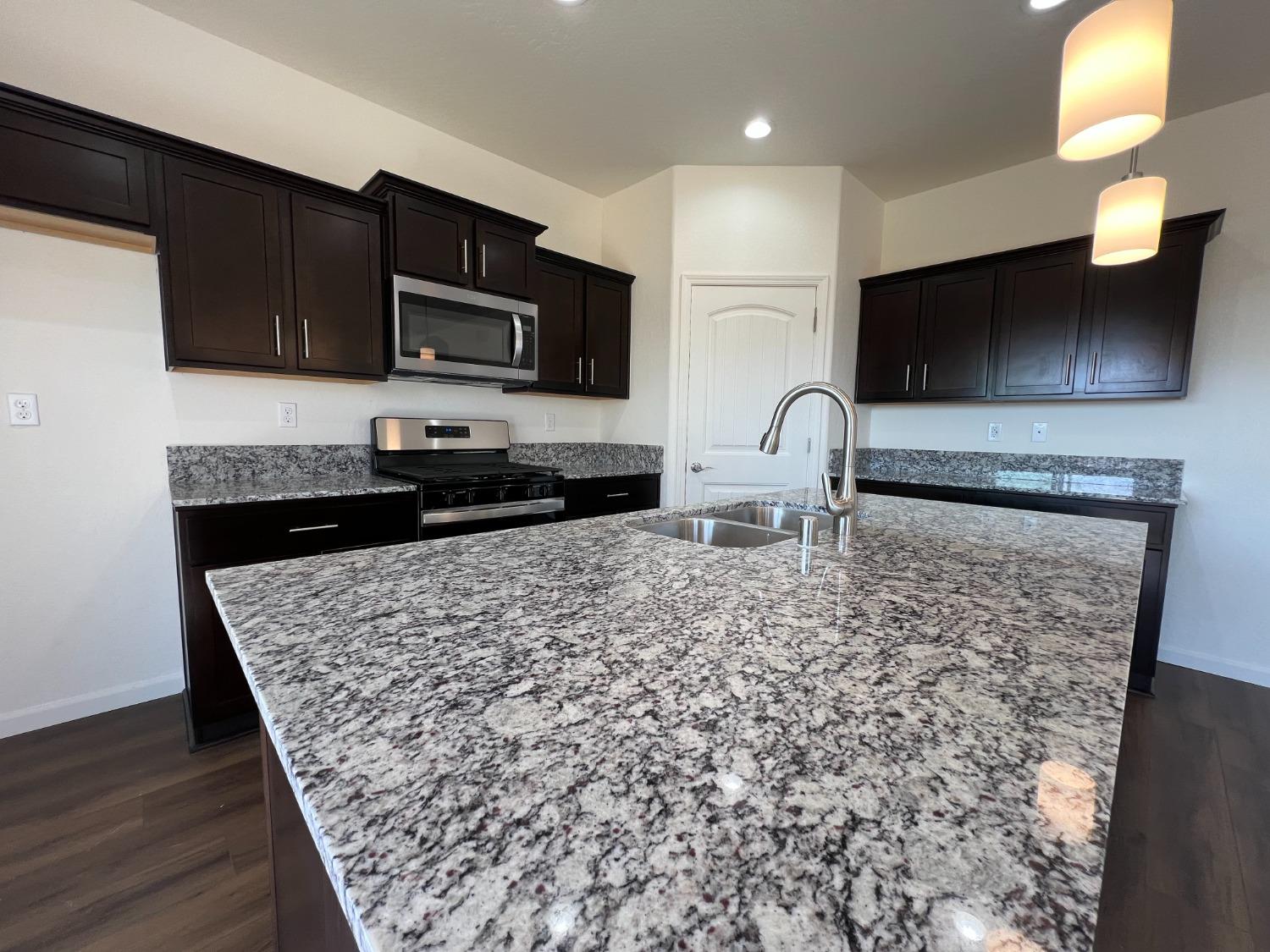 1420 Concord Way Dinuba, CA 93618 - Photo 2 of 16 a kitchen with stainless steel appliances granite countertop a stove a sink and a microwave