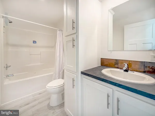 a bathroom with a granite countertop sink toilet a mirror and shower
