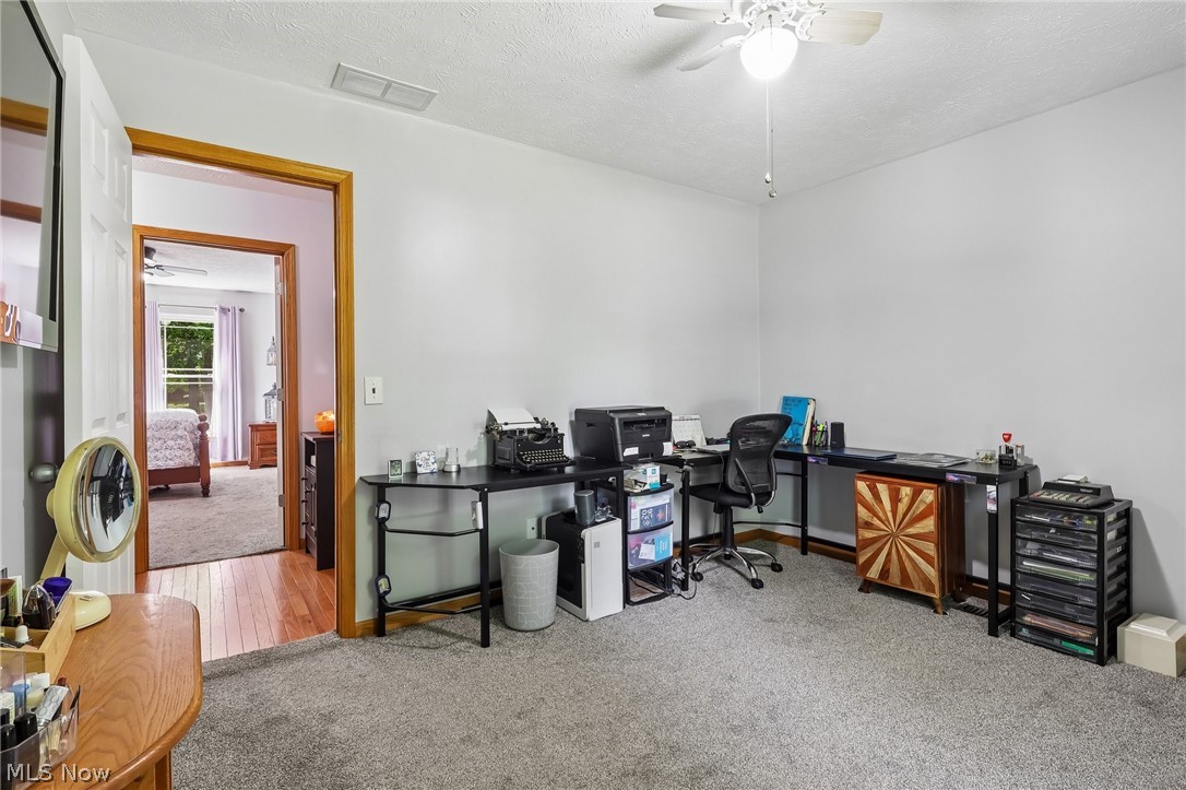 3213 Bates Road Madison, OH 44057 - Photo 25 of 45 Carpeted room featuring a ceiling fan with light fixture and a doorway with wood-finish trim leading to a room with wood-finish flooring