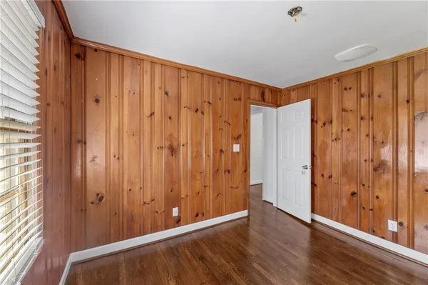 a view of a hallway with wooden floor and a bathroom