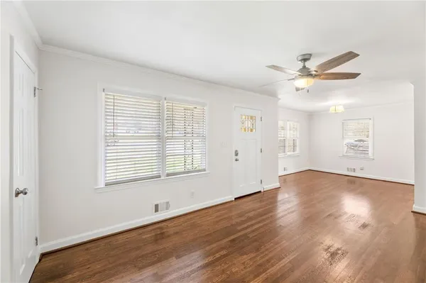 an empty room with wooden floor and windows