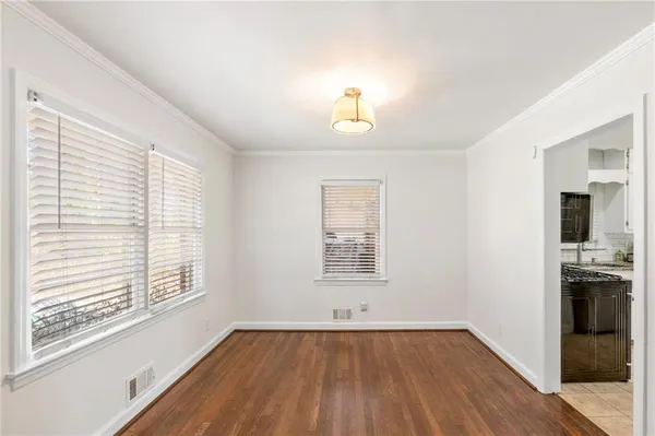 an empty room with wooden floor chandelier and windows