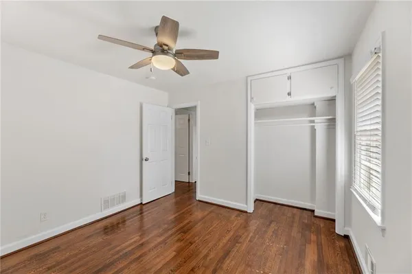 a view of empty room with wooden floor and fan