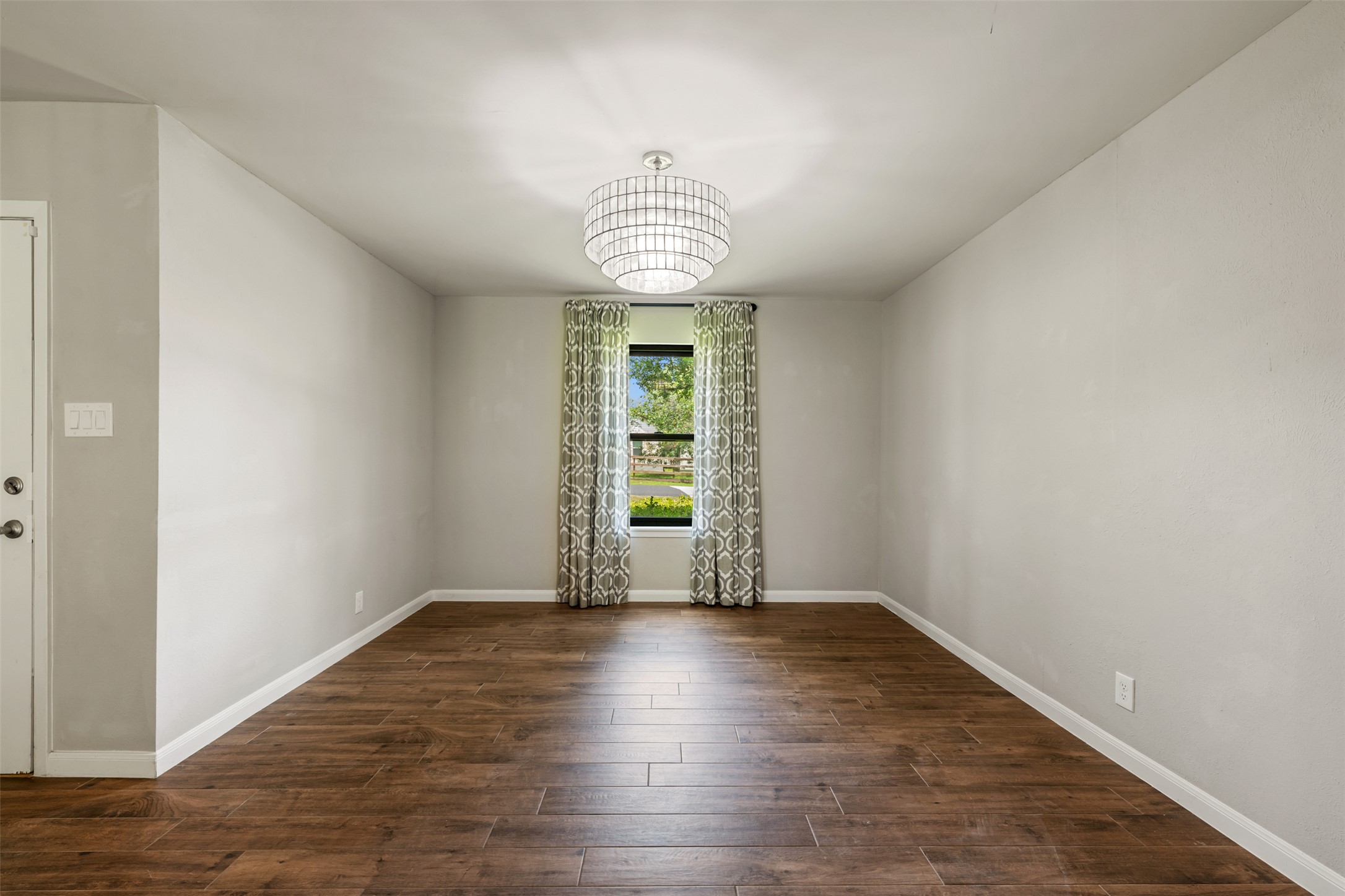 1600 Pin Oak Lane Round Rock, TX 78681 - Photo 7 of 40 Spacious room featuring wood-finish flooring, light grey wall paint, and a multi-tiered chandelier