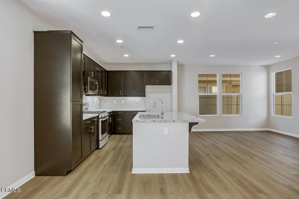 225 Stonegate Road Camarillo, CA 93010 - Photo 6 of 32 a kitchen with stainless steel appliances granite countertop a stove top oven a refrigerator a sink and dishwasher with wooden floor