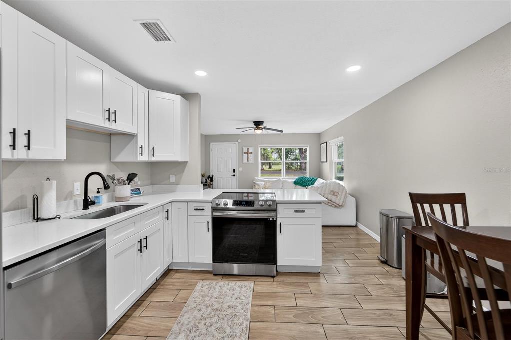 5502 Peach Avenue Seffner, FL 33584 - Photo 21 of 48 a large white kitchen with stainless steel appliances granite countertop a stove a sink a refrigerator and white cabinets
