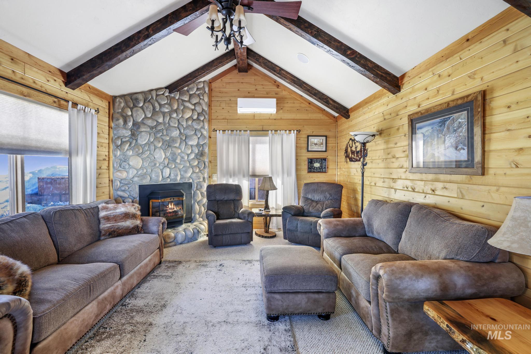 203 North Brush Road Fairfield, ID 83327 - Photo 25 of 50 Living area with wooden walls, a stone fireplace, a ceiling fan, and carpet