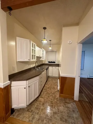 a large kitchen with granite countertop a sink and dishwasher a stove top oven with wooden floor