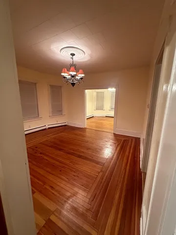 wooden floor in an empty room with a chandelier