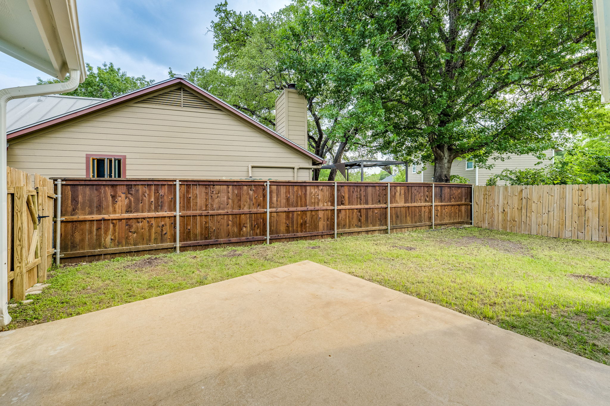 4815 Transit Circle Austin, TX 78727 - Photo 28 of 35 Expansive concrete patio overlooking the fenced backyard, offering plenty of space for relaxing, entertaining, or outdoor dining.