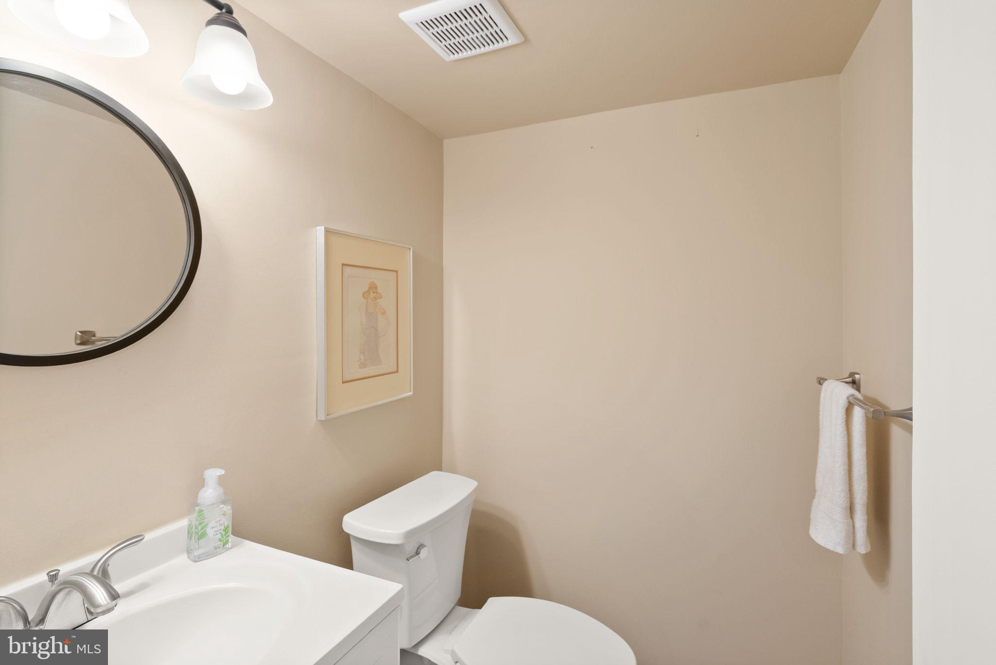 6026 Queenston Street Springfield, VA 22152 - Photo 41 of 53 a white toilet sitting next to a bathroom sink and a mirror