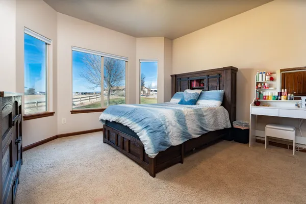a bedroom with a bed wooden floor and a large window