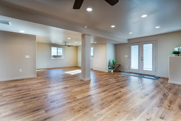 a view of an empty room with wooden floor and a window