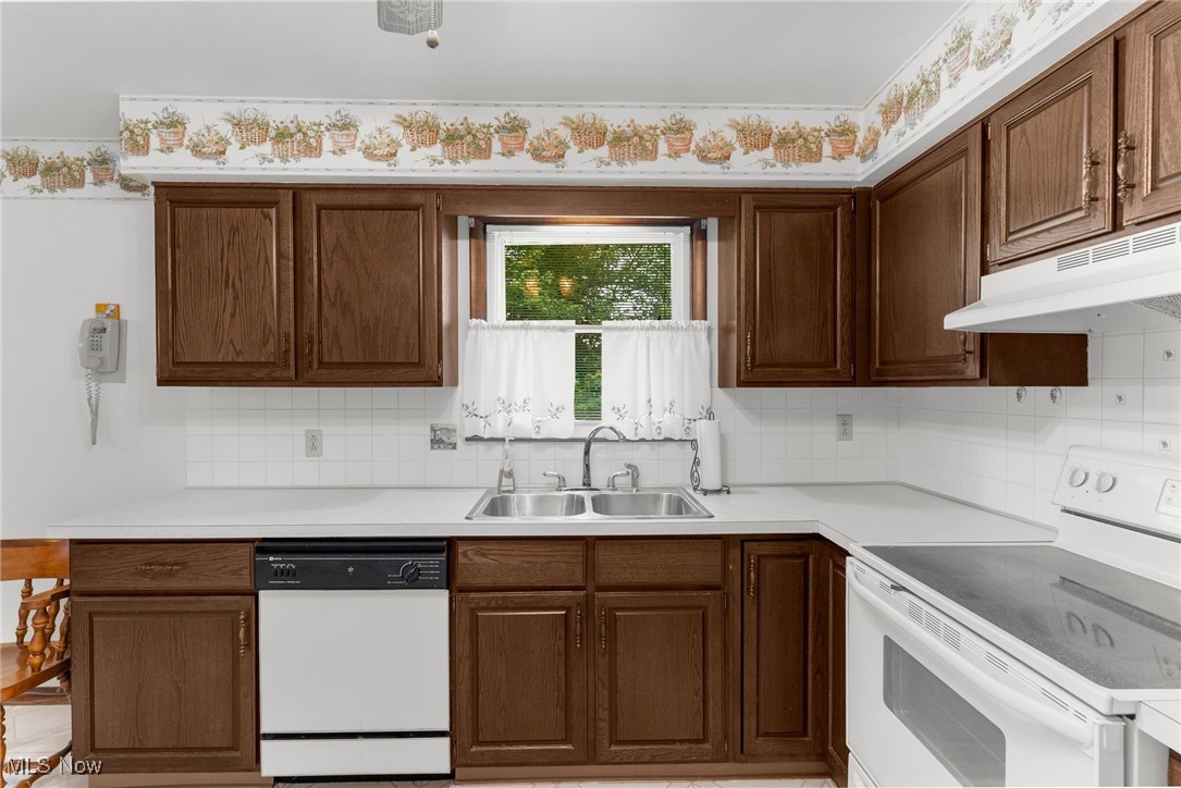 1295 Shields Road Youngstown, OH 44511 - Photo 17 of 27 Kitchen featuring white appliances, a sink, under cabinet range hood, and backsplash