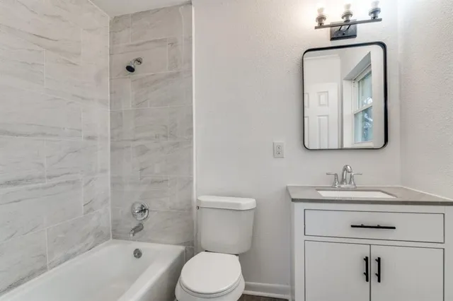 a bathroom with a toilet sink vanity tub and mirror