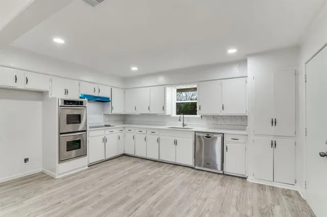 a kitchen with granite countertop white cabinets and stainless steel appliances