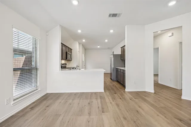 a view of kitchen with stainless steel appliances kitchen island wooden floors and living room view