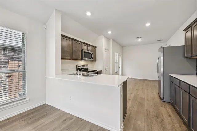 a view of a kitchen with stainless steel appliances wooden floor and chair