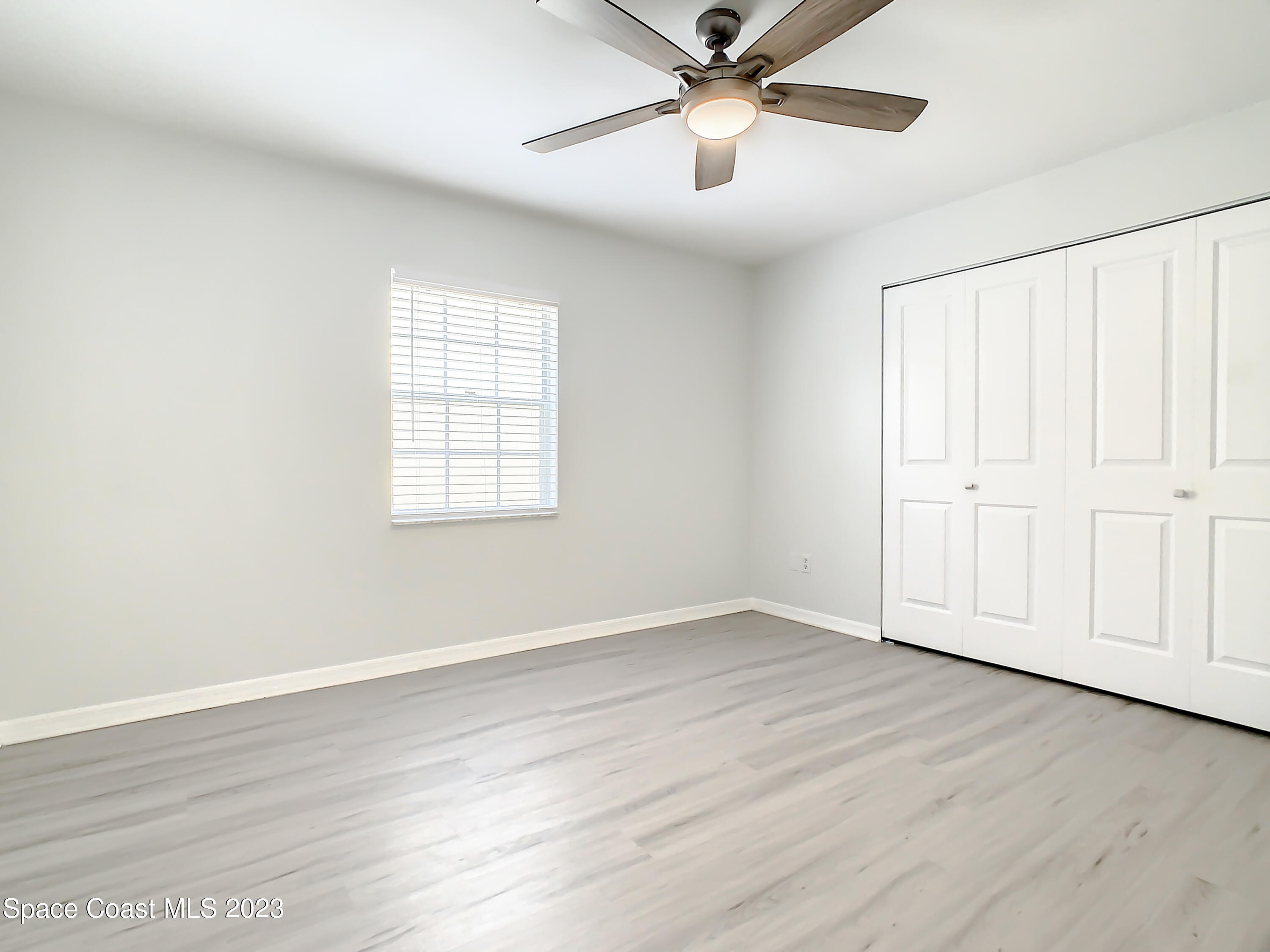 8520 Highway 1, Unit E9 Micco, FL 32976 - Photo 12 of 24 an empty room with wooden floor chandelier fan and windows