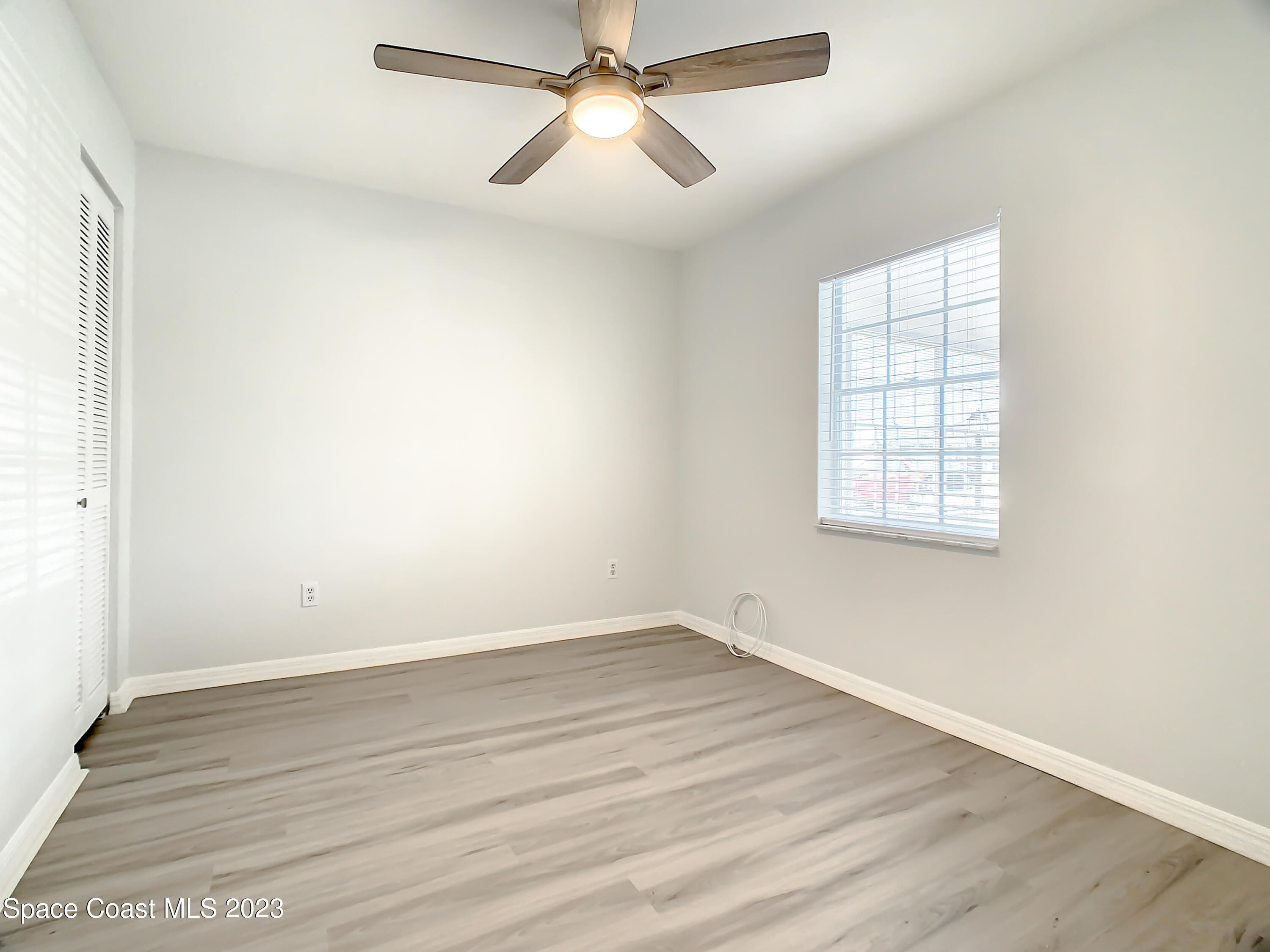 8520 Highway 1, Unit E9 Micco, FL 32976 - Photo 13 of 24 an empty room with wooden floor fan and windows