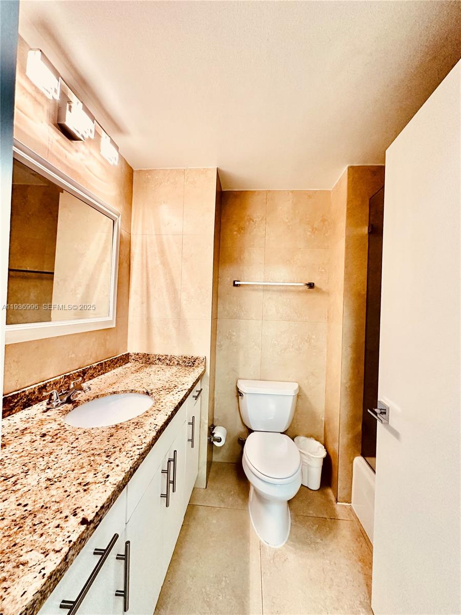 185 Southeast 14th Terrace, Unit 904 Miami, FL 33131 - Photo 13 of 19 a bathroom with a granite countertop sink toilet and shower