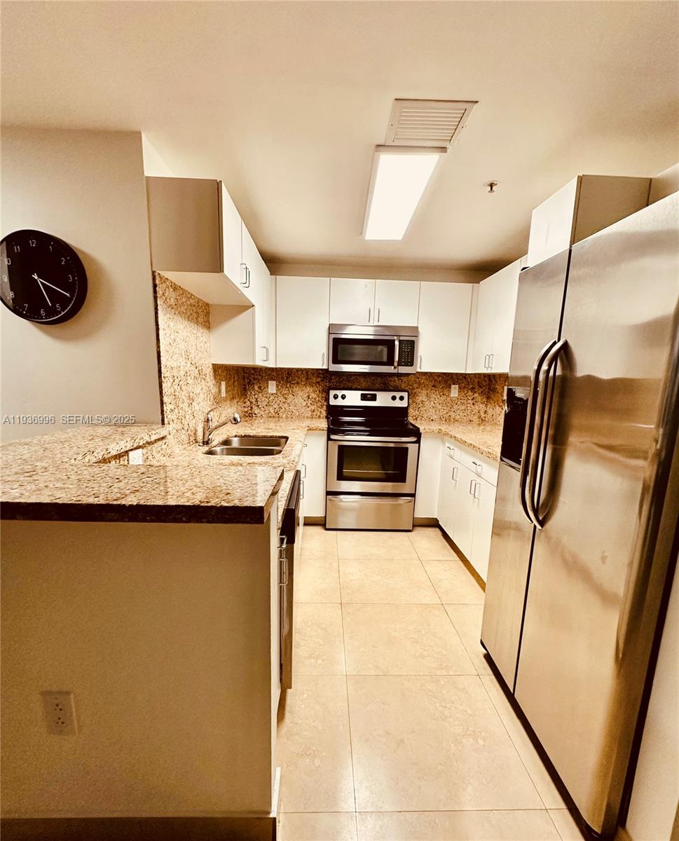 185 Southeast 14th Terrace, Unit 904 Miami, FL 33131 - Photo 8 of 19 a kitchen with stainless steel appliances granite countertop a sink a stove top oven a counter space and cabinets