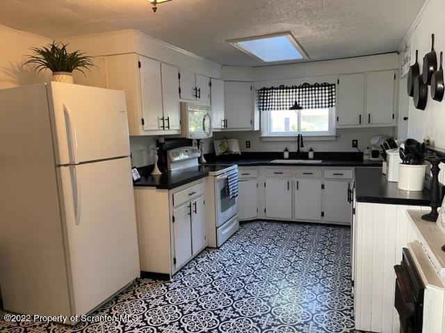 991 Main Street Rome, PA 18837 - Photo 24 of 53 a kitchen with a sink a refrigerator a stove a microwave and cabinets