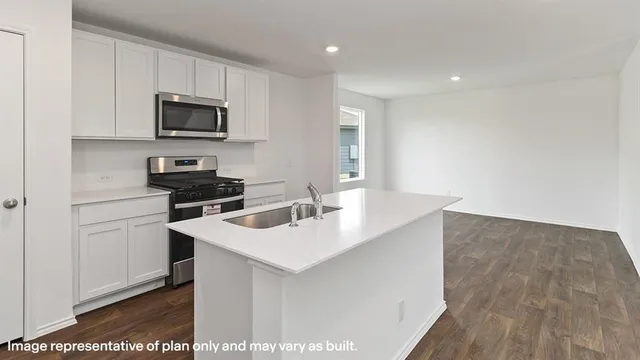 a kitchen that has a sink and a stove top oven with wooden floor