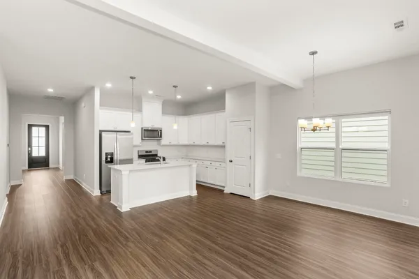 a kitchen with stainless steel appliances kitchen island wooden floors and white cabinets