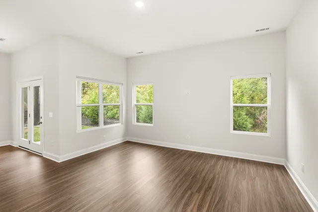 an empty room with wooden floor and windows