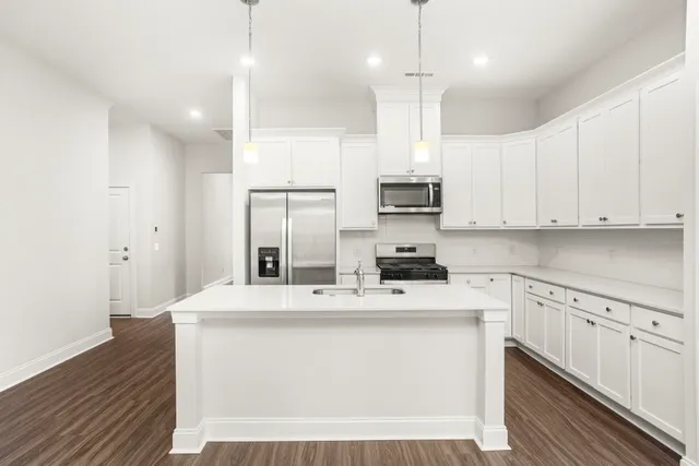 a kitchen with kitchen island a sink stainless steel appliances and white cabinets