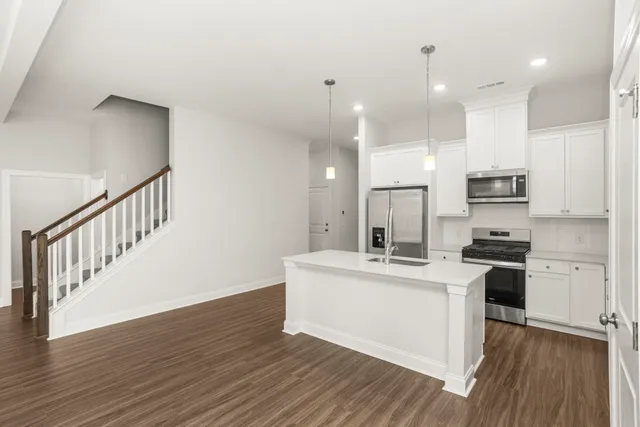 a kitchen with stainless steel appliances kitchen island a stove a sink and a refrigerator