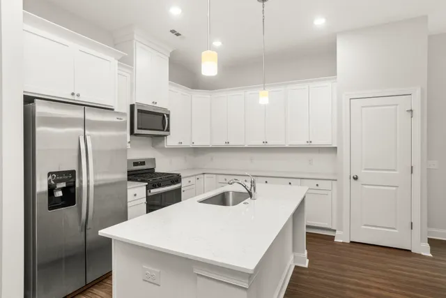 a kitchen with a refrigerator a sink and wooden floor