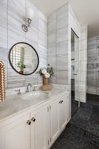 a bathroom with a granite countertop sink a mirror and shower