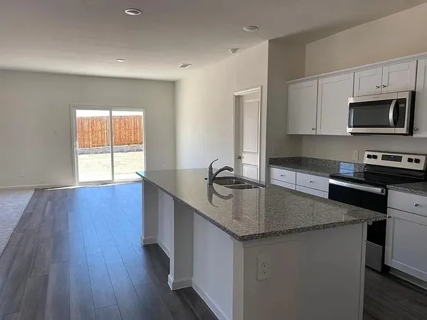 a kitchen with stainless steel appliances granite countertop a sink a microwave counter space and wooden floor