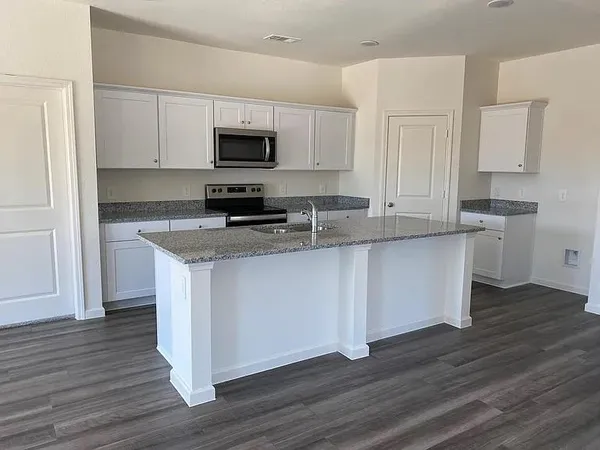 a kitchen with stainless steel appliances granite countertop a stove top oven a sink and white cabinets