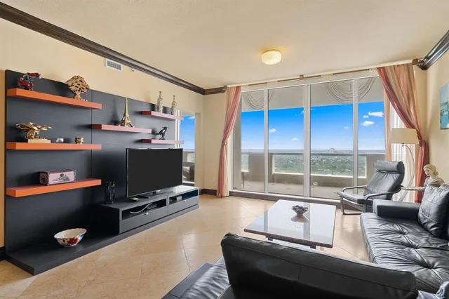 a living room with furniture a flat screen tv and a floor to ceiling window